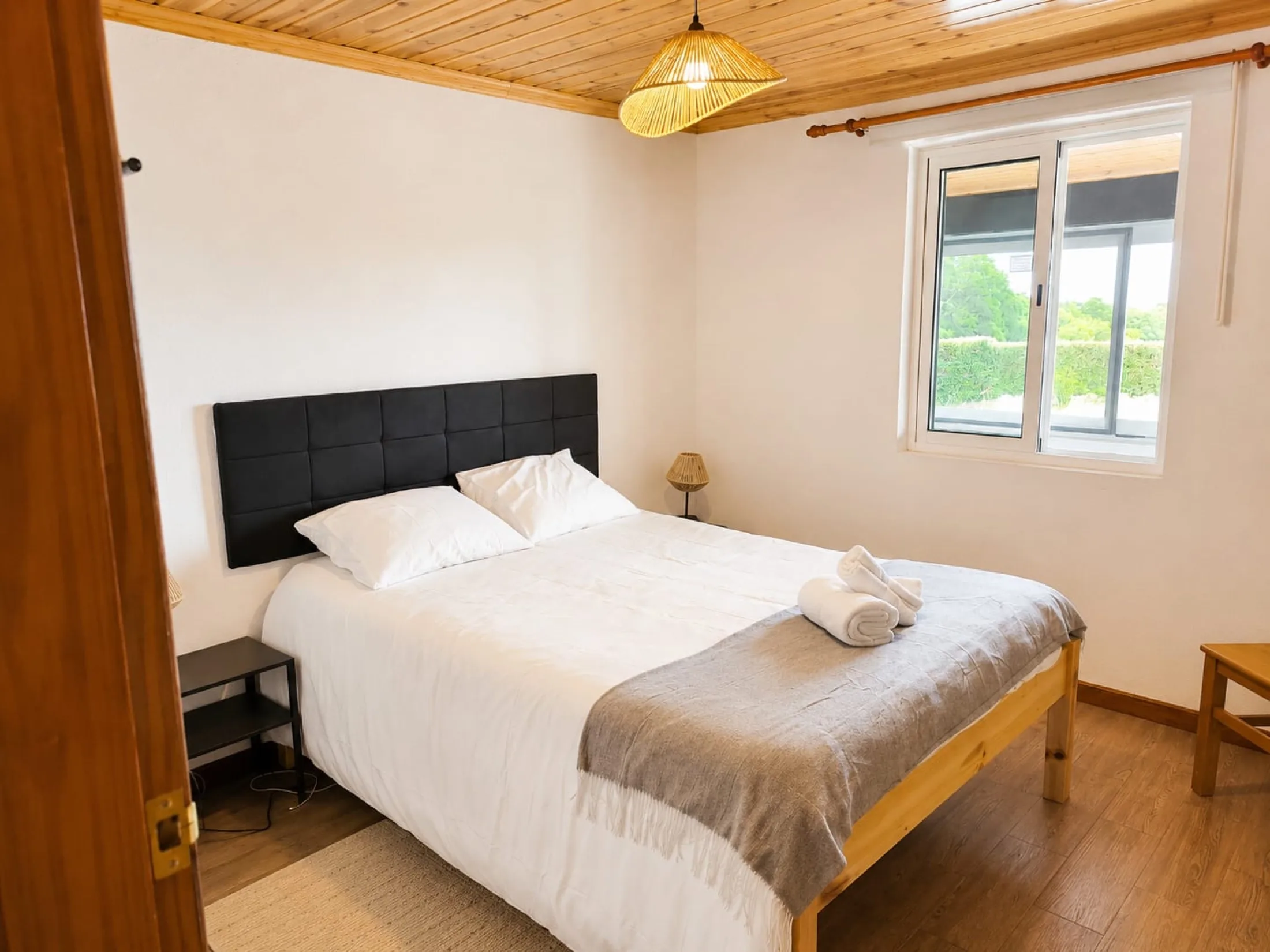 Quarto principal luminoso com cama de casal e teto em madeira